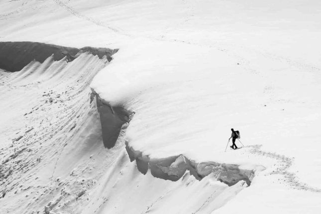 Photographie exposition 2024 Fragilité : skieur solitaire sur une corniche de neige menaçant de s'effondrer, danger et isolement.