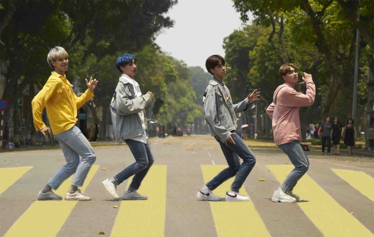 Photographie d'exposition 2025 : quatre jeunes hommes stylisés marchant sur un passage piéton (hommage Abbey Road), ambiance pop/musique.